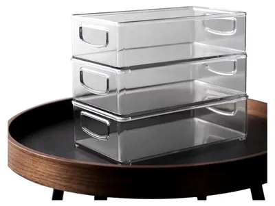 Three clear plastic storage containers are stacked on top of each other on a dark round tray.