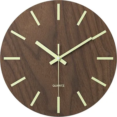 A close-up shot of a wooden wall clock with luminous hour markers and hands.