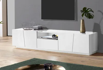 A modern white high-gloss TV lowboard with a media console and decorative vase with a plant.