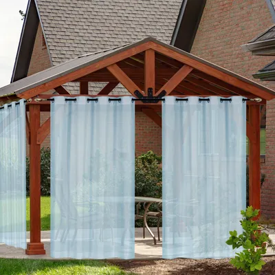 Outdoor curtains hanging from a wooden gazebo.