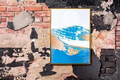 A framed picture with abstract art is hanging on a distressed brick wall.