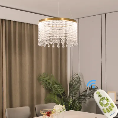 A modern dining room with a crystal chandelier, plants, and a remote control.
