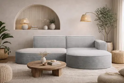 A modern living room with a light gray sectional sofa, a round wooden coffee table, and decorative elements.