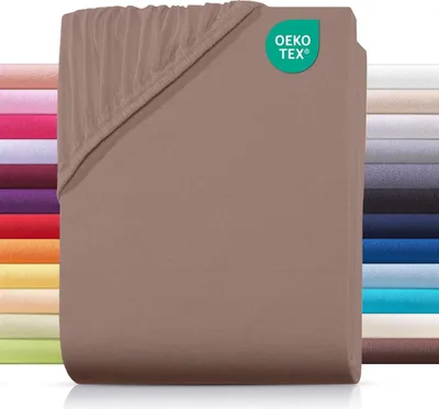 A folded fitted sheet is shown with a stack of other colored sheets in the background.