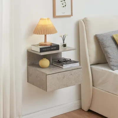 A bedside table with a lamp, books, and a vase next to a bed.