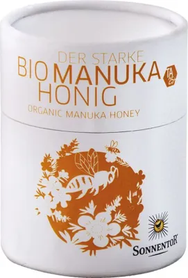 A cylindrical container of Sonnentor Manuka Honey with branding and illustrations.