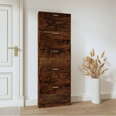 A tall, narrow shoe cabinet with five drawers is shown standing against a white wall next to a white door. A vase with dried wheat stalks is placed to the right of the cabinet.