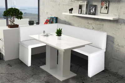 A white corner bench dining set with a white table in a modern room with a concrete wall and a large window.