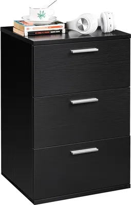 A black three-drawer nightstand with books and headphones on top.