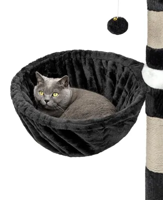 A cat is resting in a black hammock attached to a cat tree.