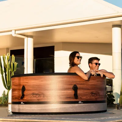 A couple relaxing in a portable hot tub on a patio.