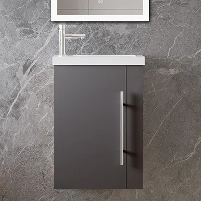 A close-up view of a modern bathroom vanity with a dark gray cabinet, a white countertop, and a silver faucet against a gray marble-patterned wall.