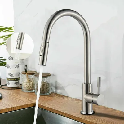 A kitchen faucet with water running, set against a tiled backsplash and a wooden countertop.