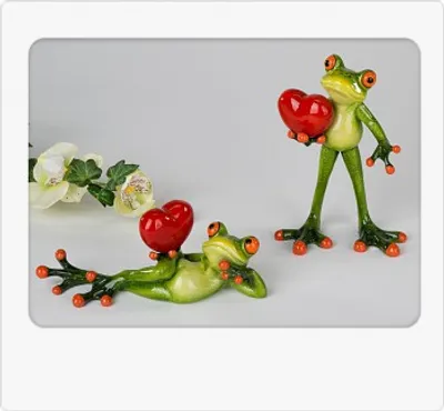 Two decorative frog figurines holding red hearts, with a white orchid in the background.