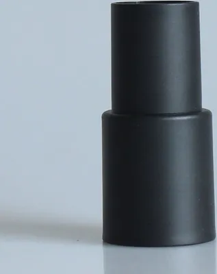 A black adapter for a vacuum cleaner hose rests on a reflective surface against a light gray background.