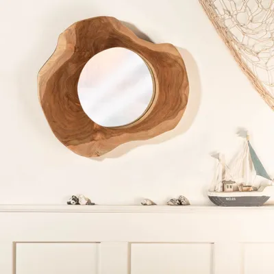A mirror with a wooden frame is displayed on a white shelf, with decorative items like a small boat and shells.