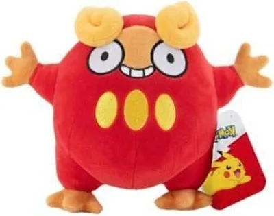 A red plush toy with yellow accents and orange limbs, standing against a white background. A tag with a Pikachu illustration is attached to its side.