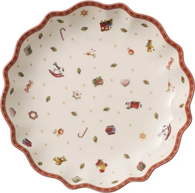 A round, scalloped-edge plate with a white background and a festive Christmas-themed pattern of toys and greenery. The rim of the plate is decorated with a red and white pattern.