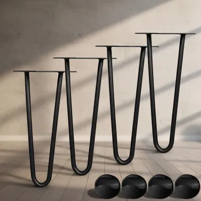 Four black hairpin legs are arranged diagonally on a wooden floor, with a textured wall in the background. Four black floor protectors are in the foreground.