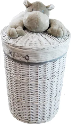 A white wicker laundry basket with a plush hippo toy on top.