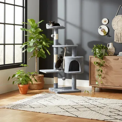 A cat tree with two cats in a living room setting.