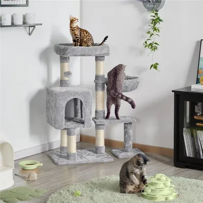 Three cats are interacting with a multi-level cat tree in a room setting.