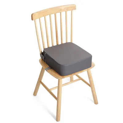 A gray booster seat is placed on a wooden chair.