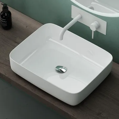 A white ceramic sink with a chrome drain sits on a wooden countertop.