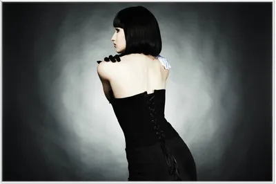 Produktbild von Wallario Wandbild Schöne Frau im schwarzen Kleid zeigt ihren Rücken, Größe: 61 x 91,50 cm, Poster mit weißem Aluminiumrahmen