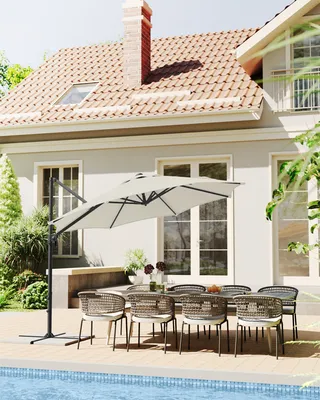 An outdoor patio scene with a table, chairs, and a large umbrella next to a swimming pool.