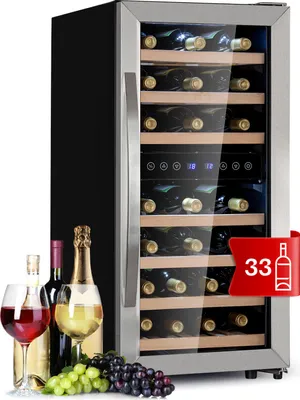 A wine refrigerator with several bottles of wine and glasses in front of it, and a cluster of grapes.