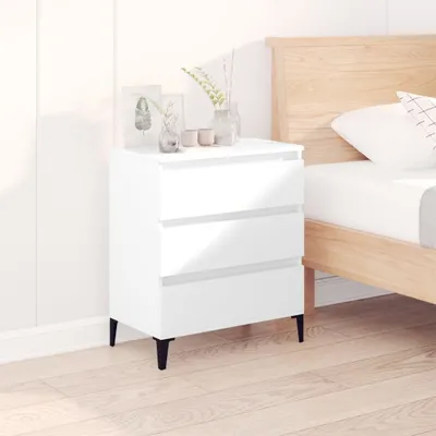 A white three-drawer dresser next to a bed in a room.