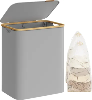 A grey laundry basket with a bamboo rim and lid, next to two laundry bags filled with clothes.