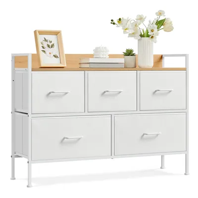 A chest of drawers with fabric drawers, decorated with a framed picture, a candle, a small plant, and a vase of flowers.