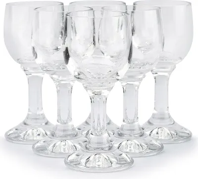 A group of six clear glass shot glasses arranged in a cluster on a white background.