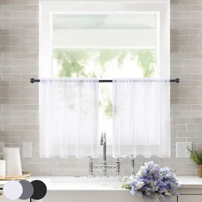 A kitchen sink area with white sheer curtains hanging in the window above.