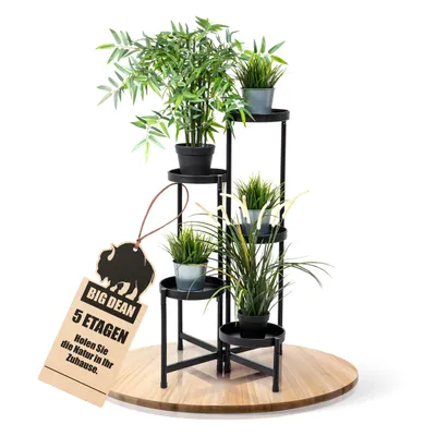 A multi-tiered plant stand with several potted plants on a wooden base, with a tag hanging from the stand.