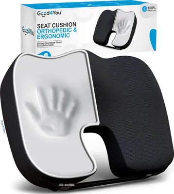 A black and white orthopedic and ergonomic seat cushion is shown in a studio setting with its packaging in the background.