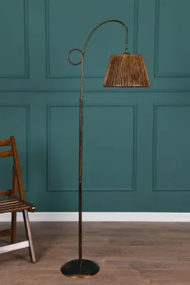 A floor lamp and a wooden chair are placed against a teal paneled wall.