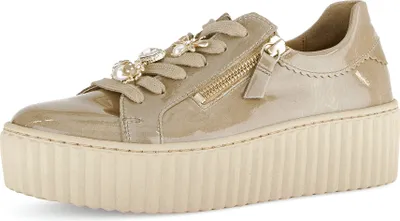 A single beige women's sneaker with a platform sole and decorative embellishments on the laces.