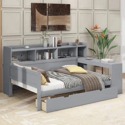 A grey daybed with storage and a pull-out drawer, styled with bedding and decorative items.