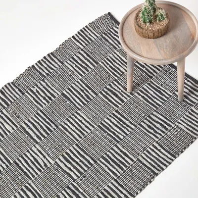 Immagine prodotto di HOMESCAPES Tappeto in pelle bianca e nera intrecciata a mano con motivo quadrato, 90 x 150 cm