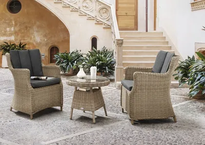 An outdoor patio setting with wicker furniture and stairs in the background.