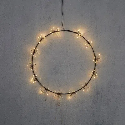 A circular LED light wreath hangs against a textured gray wall.