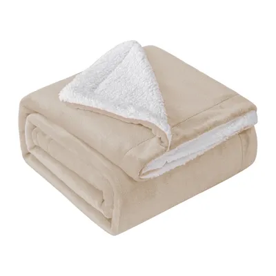 A folded beige blanket with a white sherpa lining is shown against a white background.