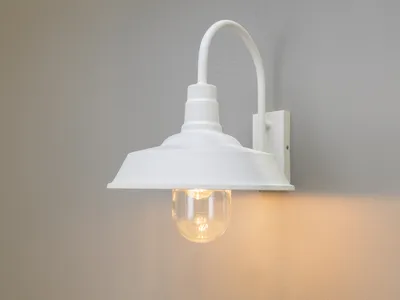 A white outdoor wall light fixture is mounted on a gray wall.
