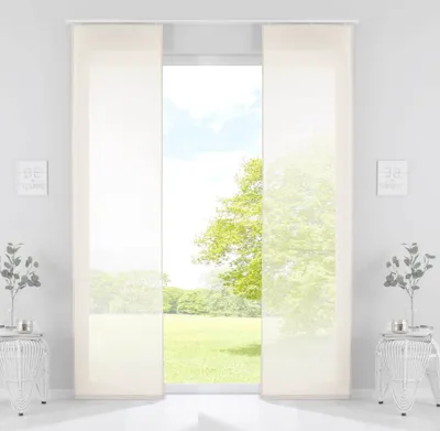 A view of a window with sheer panel curtains, showing a green lawn and trees outside.