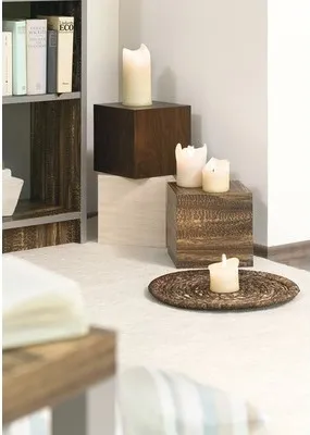 A corner of a room with decorative items, including candles on wooden blocks and a bookshelf in the background.