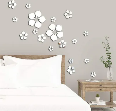 A bedroom scene with a bed and a wall decorated with 3D flower stickers.