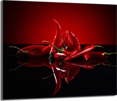 A group of red chili peppers arranged on a reflective black surface with a red background.